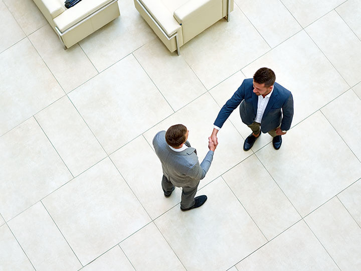 Aerial view of business partners in suits shaking hands after a successful negotiation in a spacious office lobby