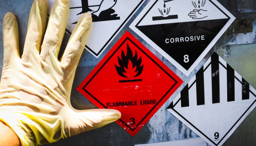 A gloved hand holds a sign warning about hazardous chemicals, emphasizing safety and caution in handling dangerous substances.