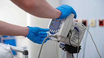 Close up view of a Healthcare professional operating a medical device while wearing blue protective gloves